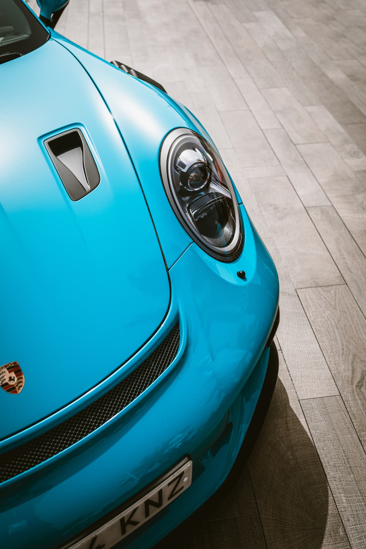 Detalle frontal de un Porsche turquesa en una sesión de fotografía de automoción